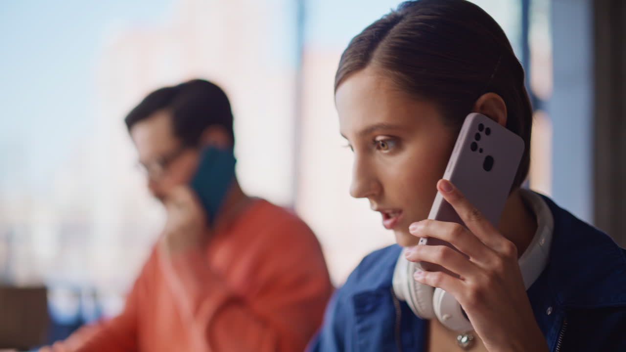 Two startupers calling mobile phones satisfied conversation in office closeup