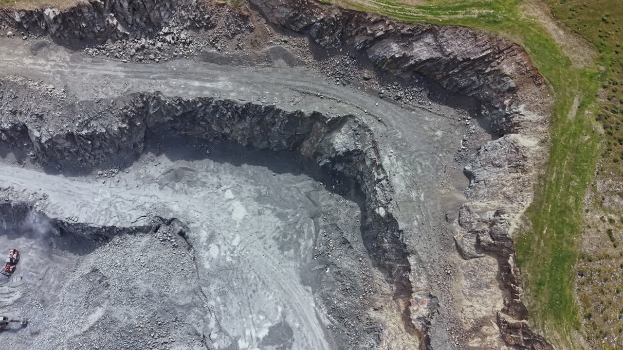 Heavy machinery works in a large quarry to extract stone and minerals in an active mining area during daylight hours