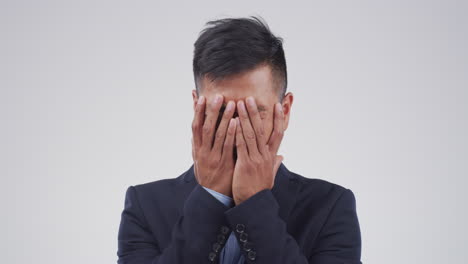 a young businessman crying against a grey