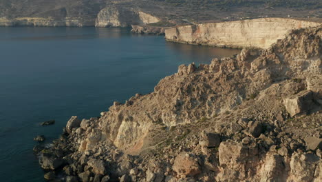 Carro-Aéreo-Hacia-Adelante-Sobre-Rocas-Marrones-Beige-En-Un-Océano-Azul-Tranquilo-Que-Revela-Agua-Turquesa-En-La-Hermosa-Luz-Del-Atardecer