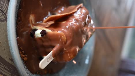 vertical footage: pouring caramel sauce on the baby dynamite dessert, which is the combination of chocolate and ice cream