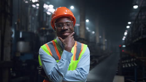 happy supervisor smiling camera wearing safety uniform at modern facility.