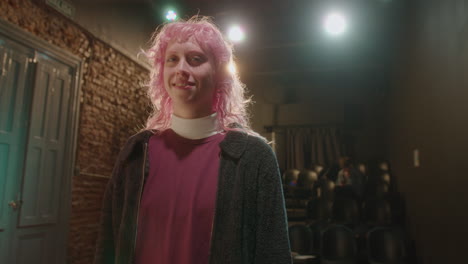 young actress with pink hair posing on theater stage