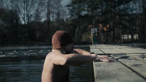 Caucasian-adult-man-going-out-of-frozen-lake-in-the-winter.