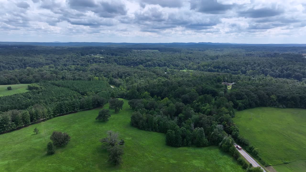 Rural road between scenic landscape, forest trees and hills of blue ridge mountains in Virginia. Aerial wide shot. Driving car on intersection, in deep woodland. Cloudy summer day in USA