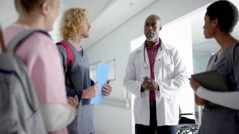 diverse doctors discussing work in corridor at hospital, slow motion