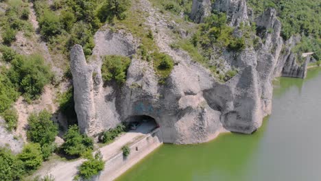 panning aerial footage of beautiful cliffs with road tunnels surrounded by lake-1