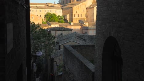 tilt down shot of ducal palace and cathedral tower in urbino district, marches, pesaro, italy on a sunny day