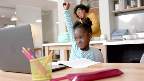 Afroamerikanisches-Mädchen-Lernt-Online-Am-Tisch-Mit-Laptop-Mit-Mutter-In-Der-Küche,-Zeitlupe