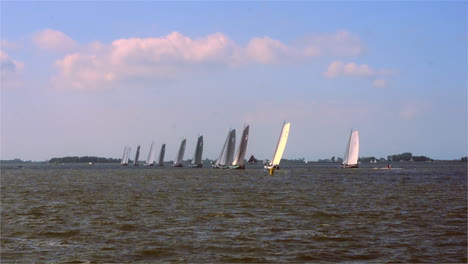 traditional sail boats crossing the regatta start line