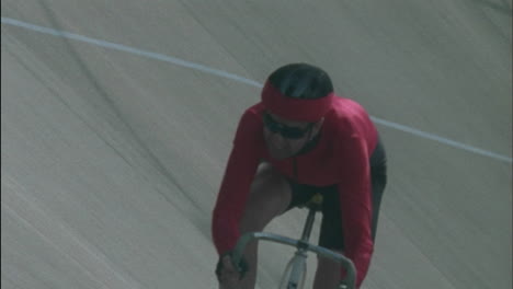 Two-men-ride-bicycles-one-smiles-and-waves-with-his-right-arm