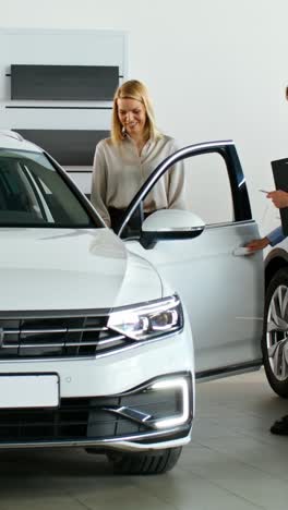 car salesperson showing a new white car to a customer