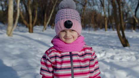 smiling child kid looking at camera, showing tongue, fooling around, making faces in winter park