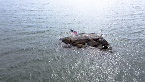 Drone-Orbita-Lentamente-Alrededor-De-La-Bandera-Americana-Soplando-En-El-Viento-En-Un-Día-Soleado-En-El-Océano-Atlántico