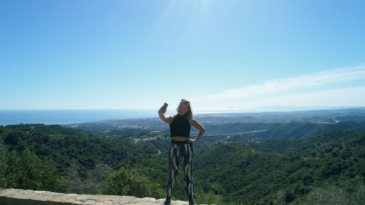 una joven excursionista se está tomando selfies en el mirador de las montañas