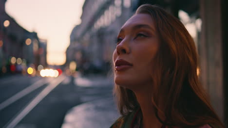 hermosa mujer de negocios de pie tarde en la noche en la calle disfrutando del paisaje urbano de cerca