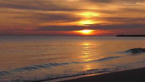 Sonnenaufgang-Strandblick-Mit-Ruhigen-Wellen-Und-Glühender-Sonne-Am-Horizont,-Mittelmeerküste-Spaniens