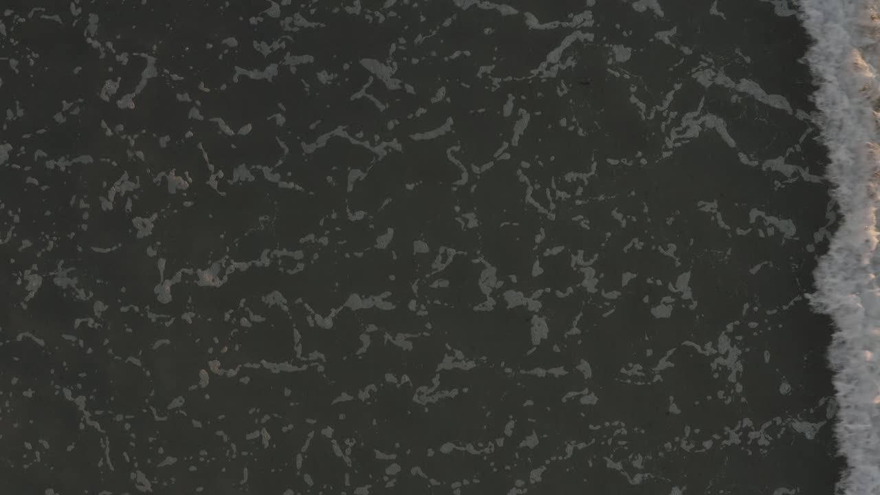 olas hipnóticas rompiendo a lo largo de la costa se disipa la espuma