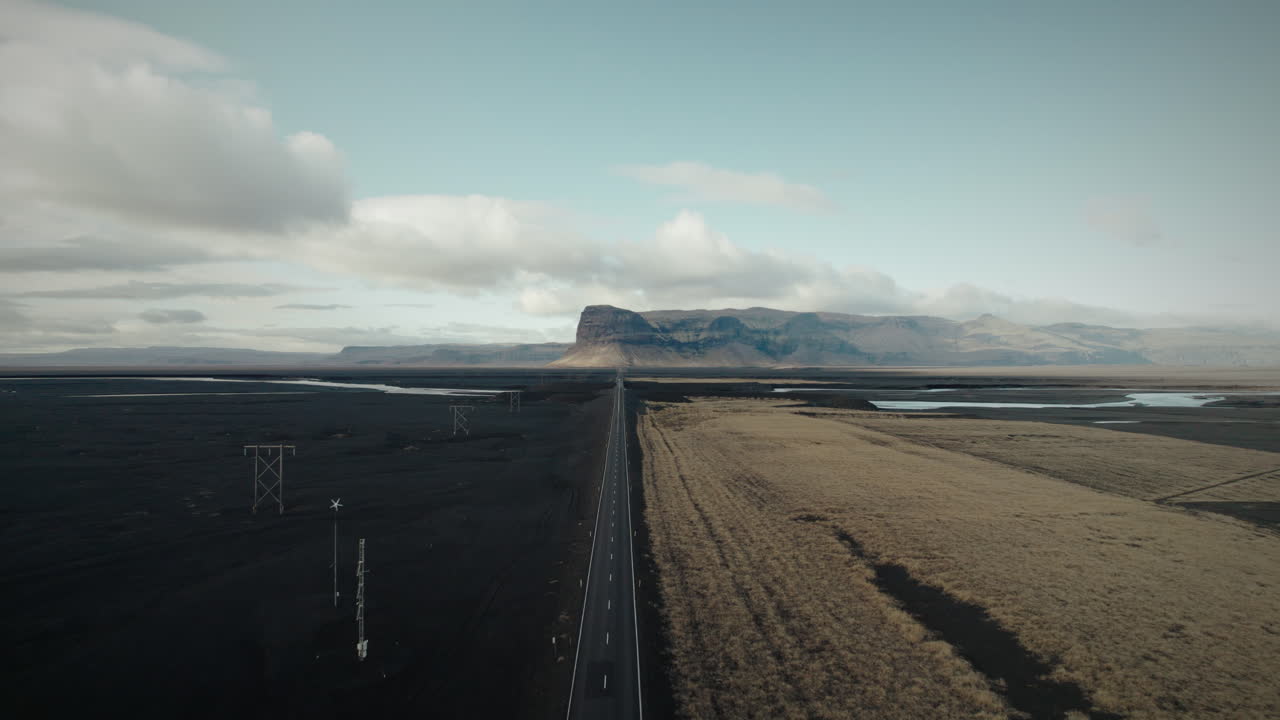paso elevado por encima de una carretera larga y recta a través del desierto de arena negra en islandia