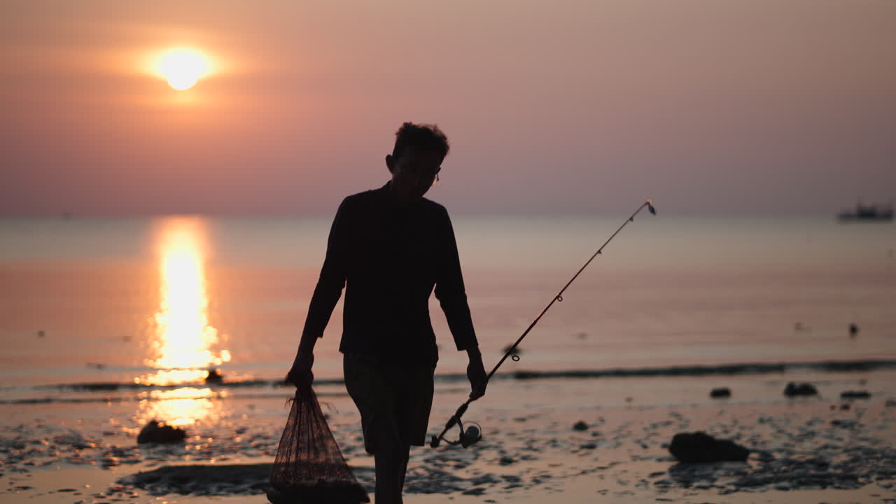 Seorang pria memancing di pantai saat matahari terbenam