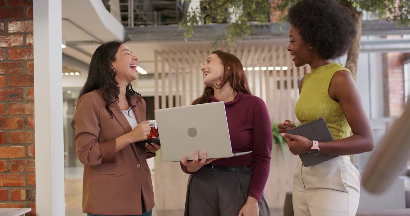 Colleghe eterogenee si riuniscono dopo che la persona al centro ha presentato il laptop, reagendo e ridendo in ufficio.