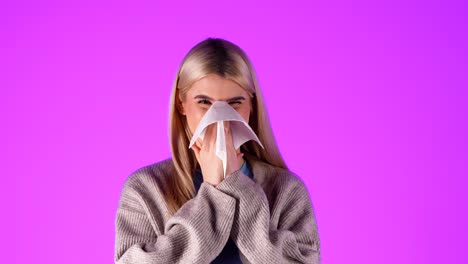 portrait shot of caucasian blonde young woman sneezing and blowing her nose at infinite magenta studio chroma background