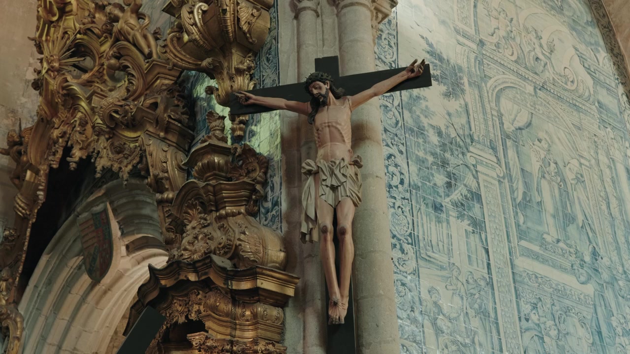 Figura lignea di Cristo crocifisso su una parete di piastrelle azulejo blu e intaglio dorato in chiesa.