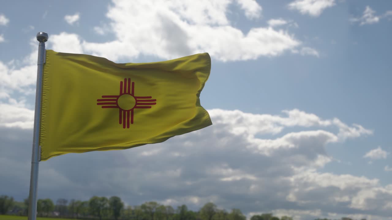 bandera de nuevo mexico en un asta de bandera ondeando en el viento, fondo de cielo azul