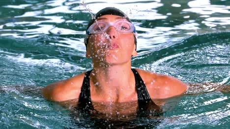 funny female swimmer spouting water to camera in the swimming pool