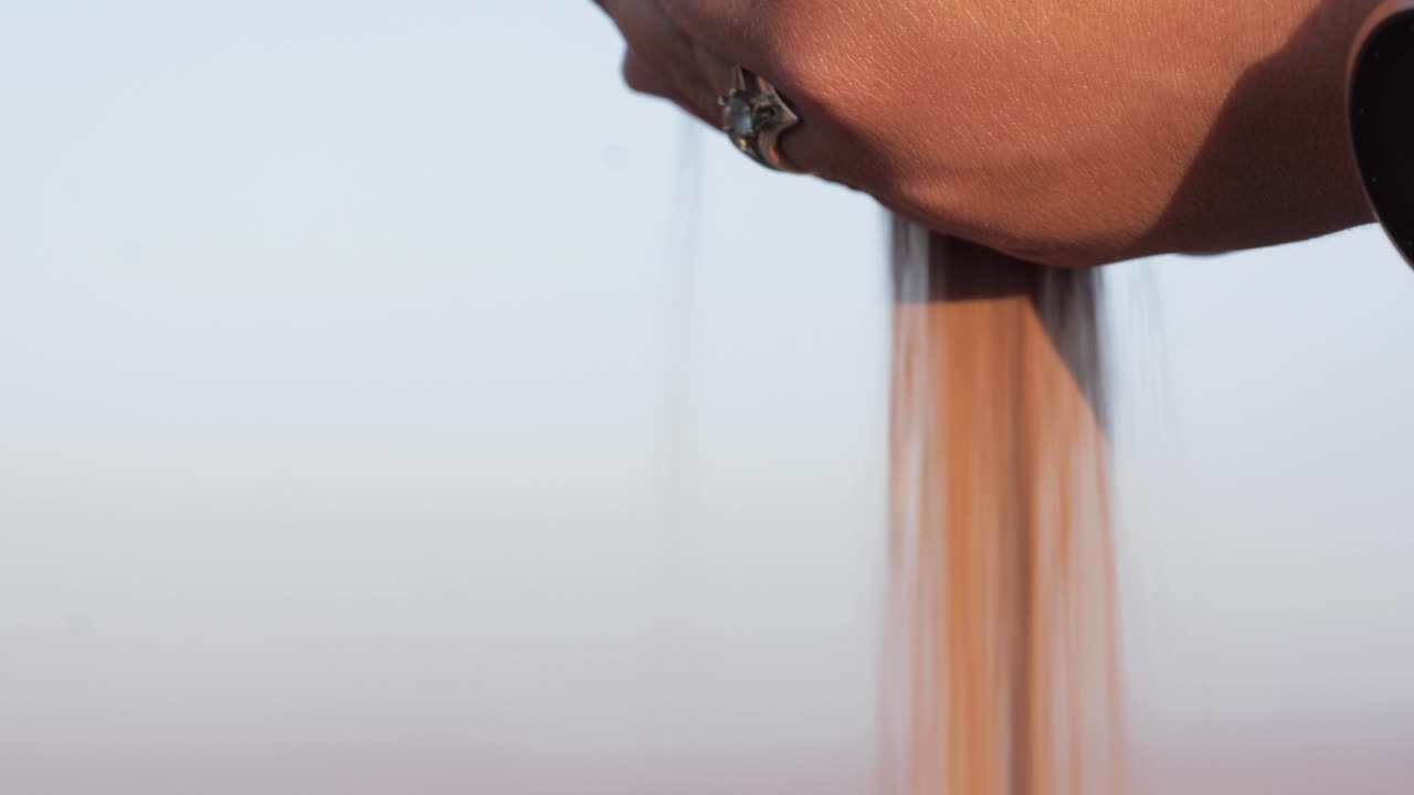 Woman's hands pour sand, capturing the essence of summer, with grains falling freely