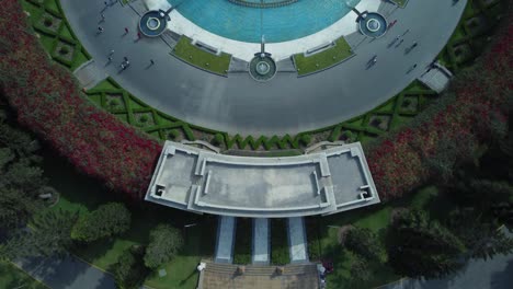 Drone-video-tilting-camera-up-showing-a-circular-water-fountain-and-behind-it-a-long-rectangular-fountain