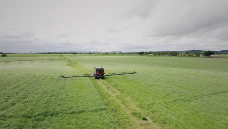 tractor operating a continuous spray machine on a farm rotating aerial shot