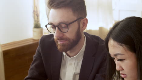 young professional woman explaining something to her colleagues while sitting at table during a team meeting 2