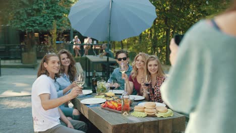 group of friends drinking wine and taking photos on phone.