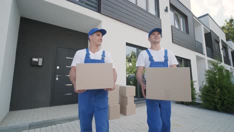 two young workers of removal company are loading boxes and furniture into a minibus