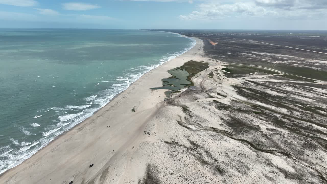 Golden sandy beach with water waves, aerial shot of Jericoacoara coastline