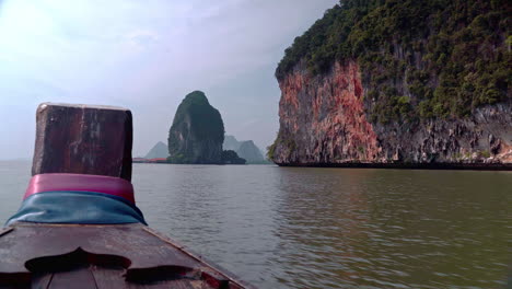 Passenger-view-from-wooden-boat-bow-sailing-past-sea-cliffs,-Thailand