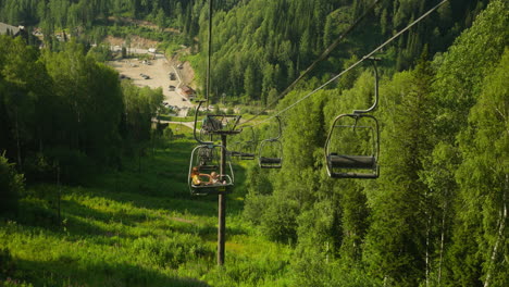 tourists descend on funicular contemplating stunning view. young people admire aerial view of astonishing resort with dense woodland and high mountains