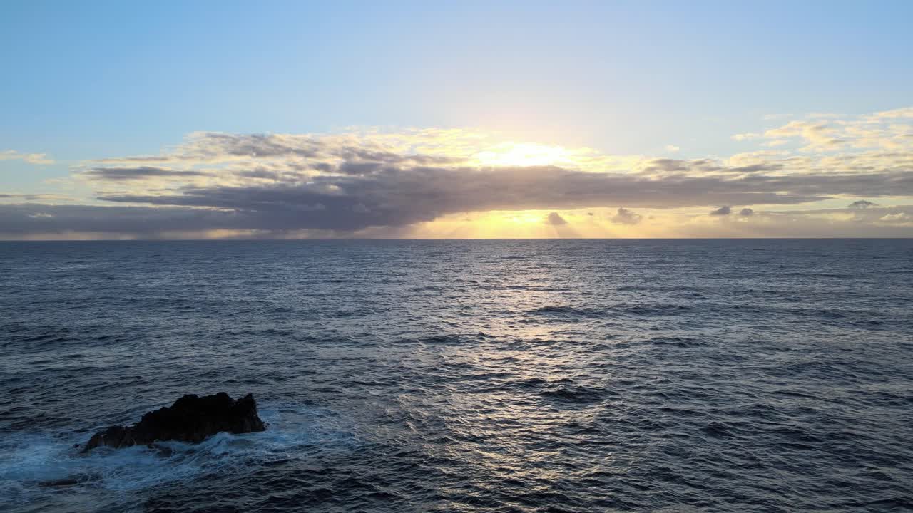 Gently gliding above, a drone observes the rhythmic dance of waves moving toward the shore as the sun sets over the picturesque landscape of Big Island, Hawaii