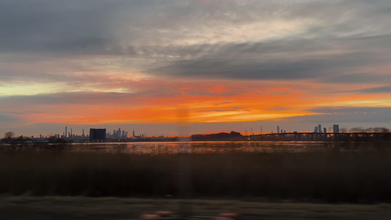 Car POV at sunset showing Manhattan skyline with warm sky colors