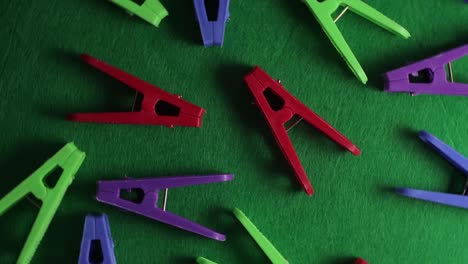 colored clothespins on a green textured background, top view, close-up, bright backdrop.