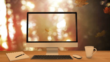 desktop computer and office equipment on a table against autumn maples leaves falling in background