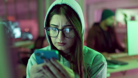 woman using smartphone in a tech office at night