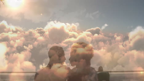 animation of blue sky and clouds over biracial couple kissing at beach