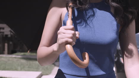 tight shot of hand holding the curved handle of an umbrella while walking down the street