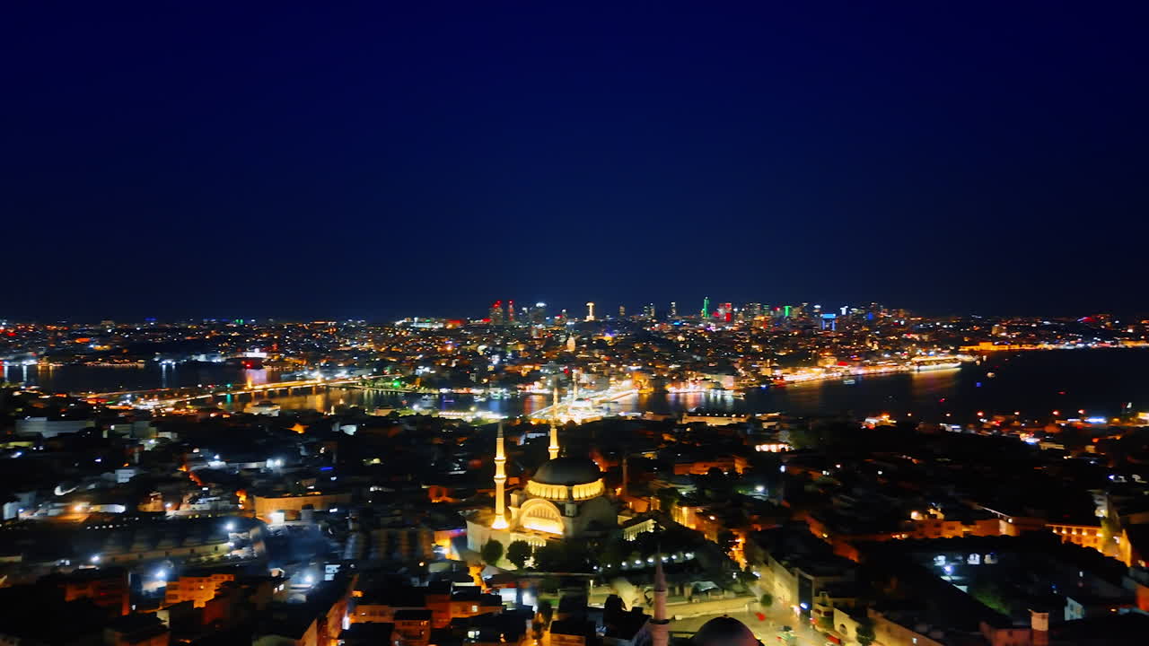 Night cityscape of the beautifully lit city with a mosque in the center. Footage over Kemer, Turkey with stunning illumination