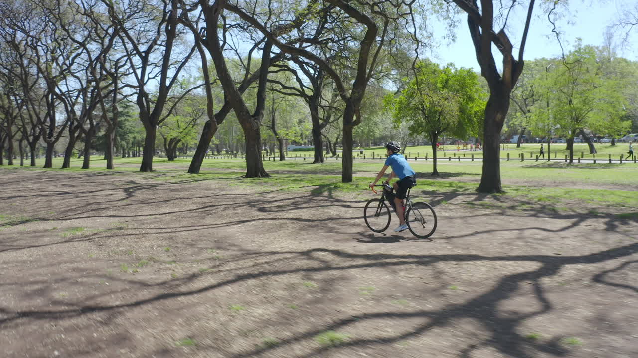 Man Cycling along Park Alley on Summer Day
