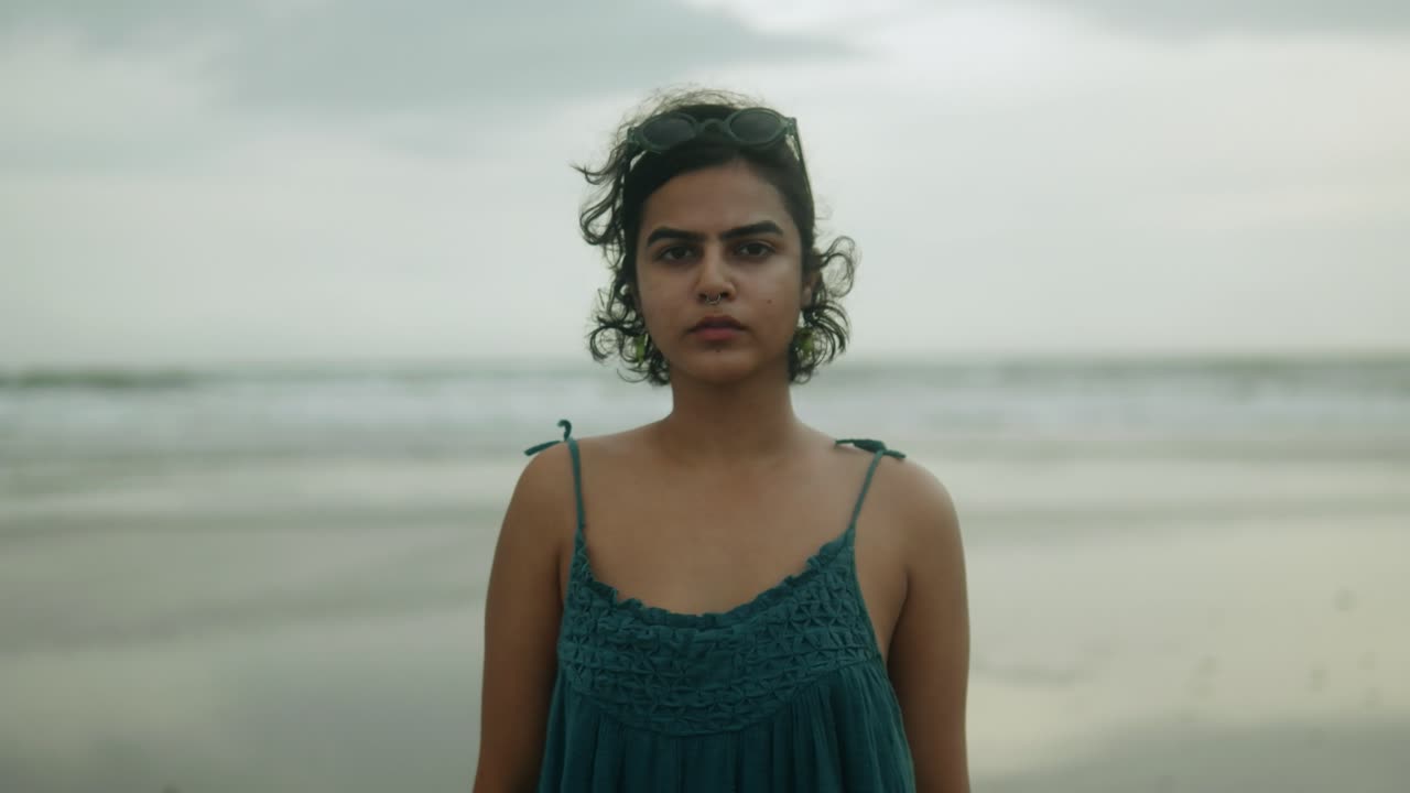 cerca de una hermosa mujer asiática de pie en la playa en un día nublado con el viento ligero soplando a través de su cabello