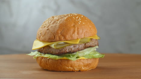 Yummy-fast-food-concept.-Fresh-homemade-grilled-burger-with-meat-patty-tomatoes-cucumber-lettuce-onion-and-sesame-seeds.-Unhealthy-lifestyle.-Food-background.