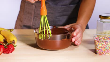 mixing chocolate with bananas and strawberries nearby